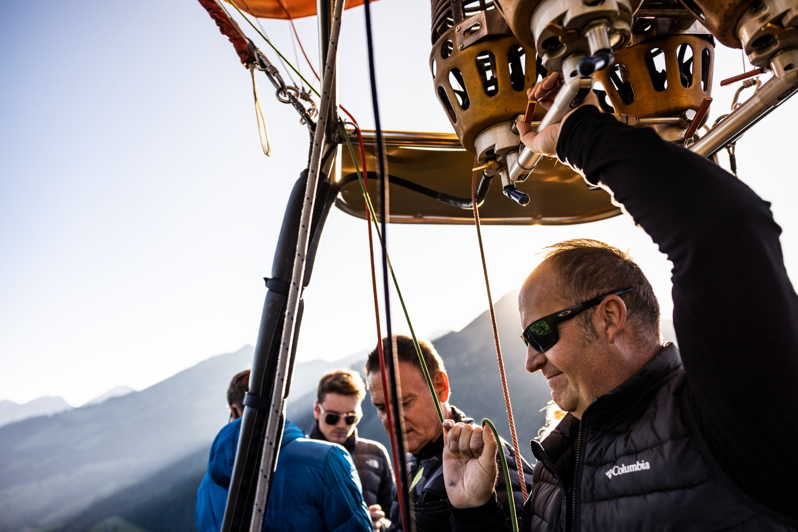 Un vol en montgolfiere au depart de Chateau-d'Oex permet aux hotes de decouvrir de pres le panorama alpin suisse vu du ciel. Une personne explique et montre le panorama des montagnes depuis la montgolfiere.